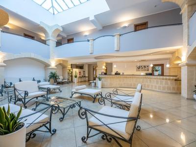 Hell beleuchteter Hotellobby-Bereich mit Sitzgelegenheiten, Säulen und offenem Atrium.