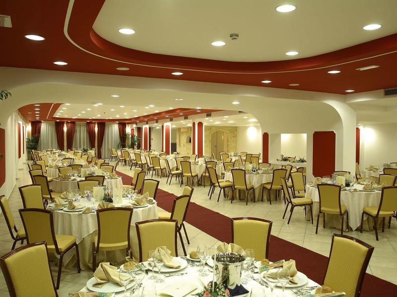 Large, festively set dining room with yellow chairs and red accents on walls and ceiling.