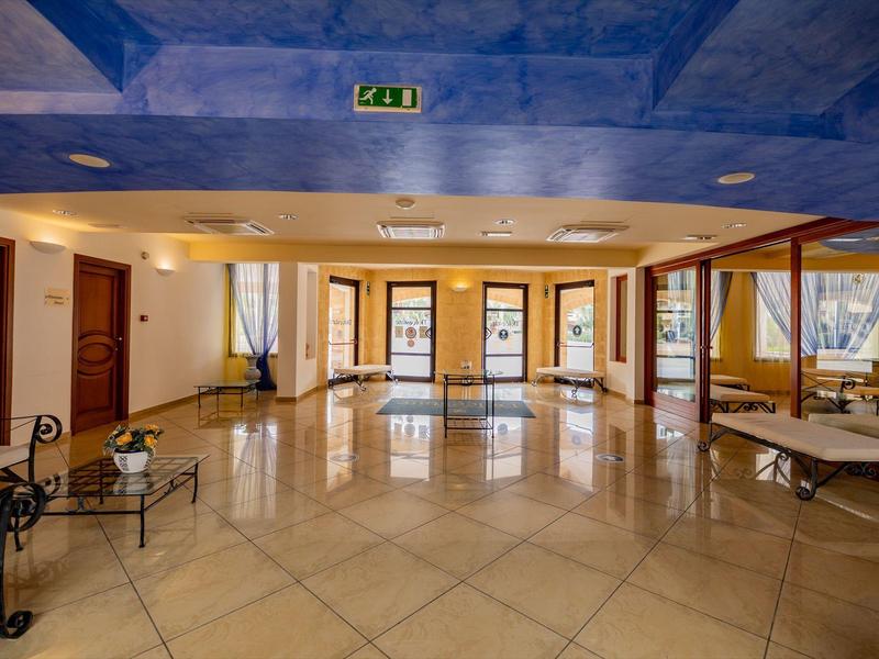 Large room with shiny floor, multiple doors, and blue ceiling area in a hotel.