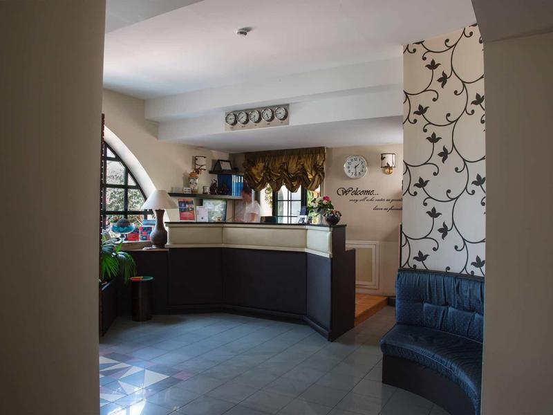 Moderner Empfangsbereich mit dunklem Tresen, großem Fenster und dekorativer Tapete in warmem Licht.