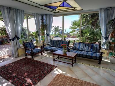 Soggiorno luminoso con divani blu, tappeti e vista su un giardino verde.