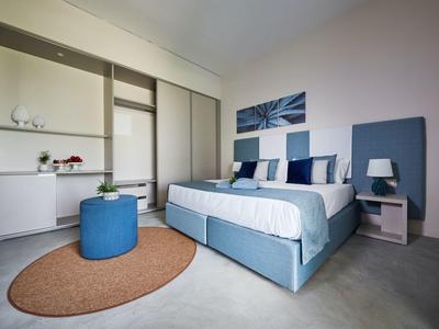 Chambre moderne avec lit bleu, table de chevet et tapis rond.