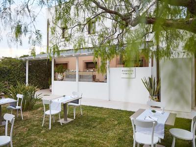 Coin extérieur convivial avec tables et chaises blanches sur pelouse verte devant un bâtiment moderne.