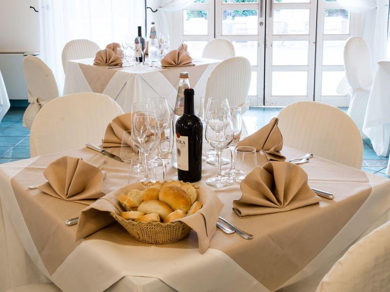 Table élégante de restaurant avec bouteille de vin, verres à vin, panier de pain et serviettes pliées.