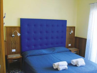 Chambre moderne avec tête de lit bleue, lit double et deux serviettes blanches roulées.