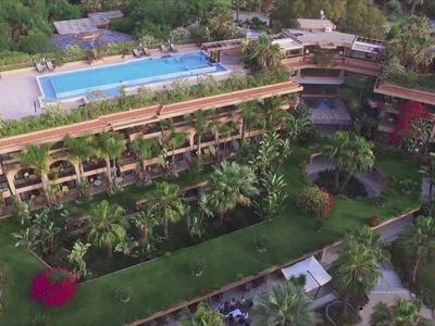 Vue aérienne d'un hôtel avec une piscine sur le toit et un environnement verdoyant.