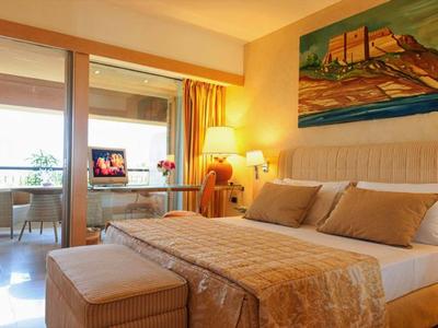 Chambre d'hôtel confortable avec lit double, tons neutres et balcon avec vue sur la mer.