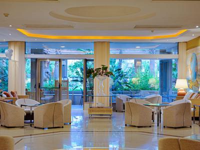 Heller Hotellobby mit bequemen Sesseln, großen Fenstern und Blick auf grüne Pflanzen.