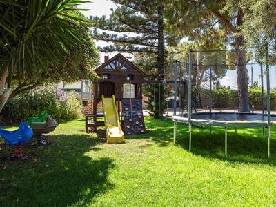 Zona de juegos infantil con tobogán, muro de escalada y trampolín en el jardín