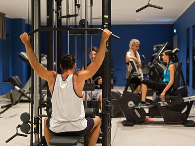 Varias personas entrenan en un gimnasio moderno con pesas y equipos de ejercicio.