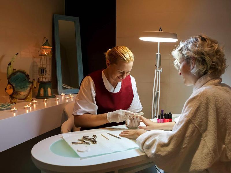 Dvě ženy při manikúře v útulném, teple osvětleném pokoji.