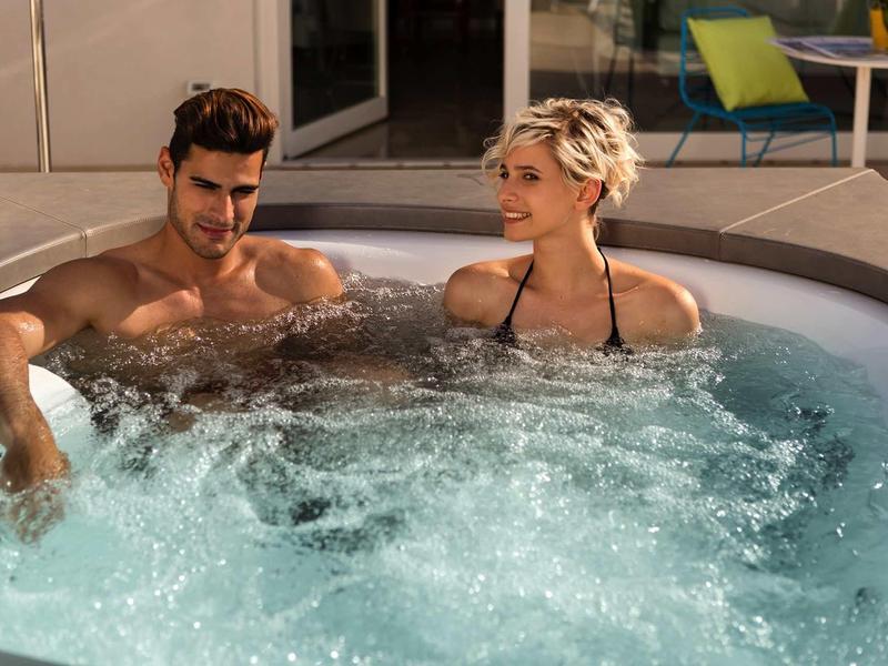 Pár relaxuje v vířivce na hotelové terase za slunečného počasí.