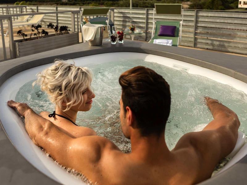 Pár relaxuje společně v venkovní vířivce na terase.