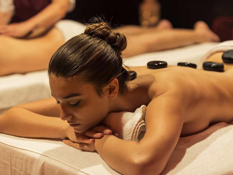 Žena relaxuje při masáži horkými kameny na masážním stole.