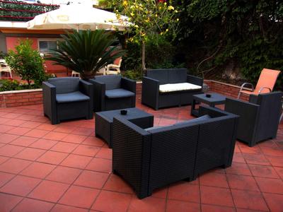 Modern seating area with black upholstered furniture on red tiled outdoor floor.