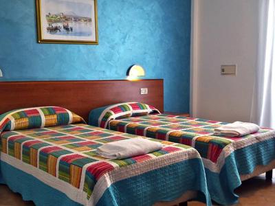 Room with two single beds, colorful blankets, and blue accent wall.