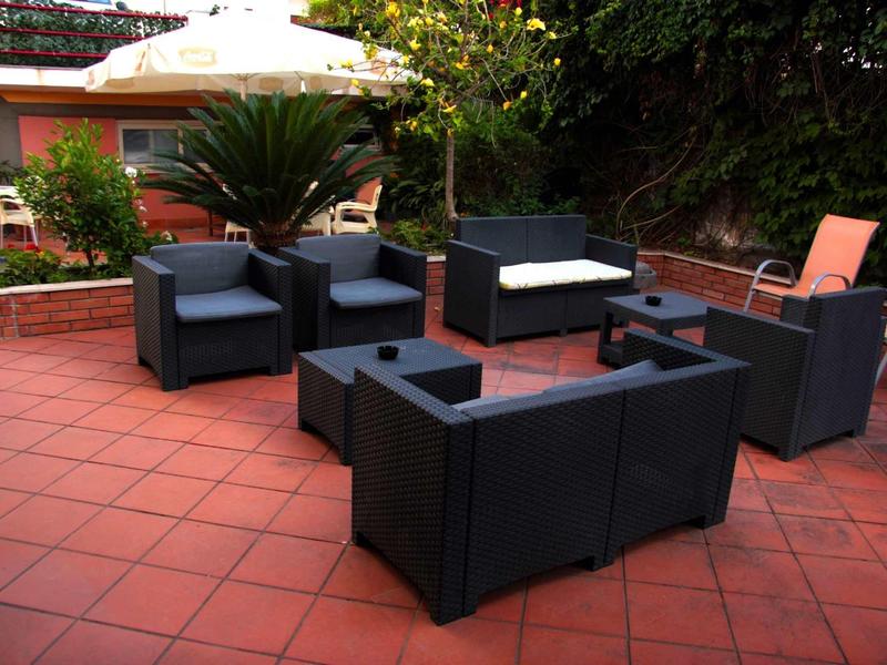 Modern seating area with black upholstered furniture on red tiled outdoor floor.