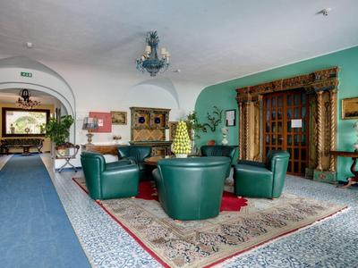 Lichte hotellounge met groene lederen stoelen en tapijt op de vloer.