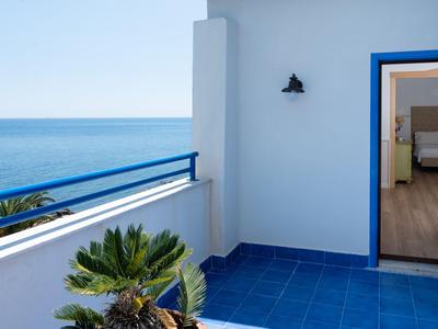 Balkon met blauwe vloer, witte muur, uitzicht op zee en toegang tot een slaapkamer.
