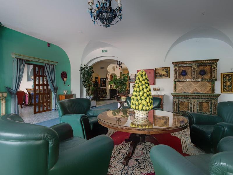 A cozy lounge with green armchairs, a round wooden table, and decorative wall in a hotel.