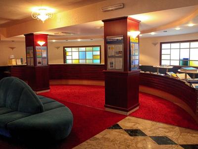 Intérieur d'un hall d'hôtel avec sièges élégants et fenêtre en verre coloré.