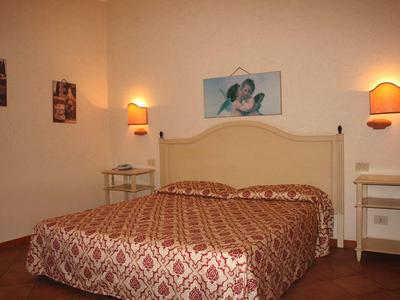 Chambre confortable avec lit double, tables de nuit et lumières murales chaudes.