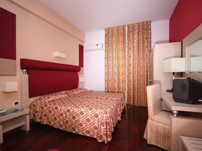 Chambre d'hôtel avec grand lit, rideau à motifs et télévision sur le bureau