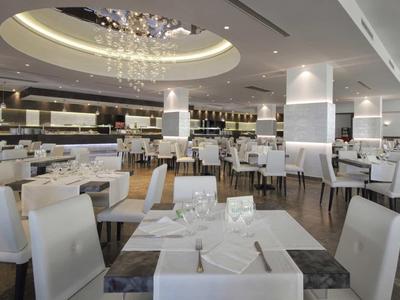 Salle à manger moderne et élégante avec des chaises blanches et un lustre décoratif dans un hôtel.
