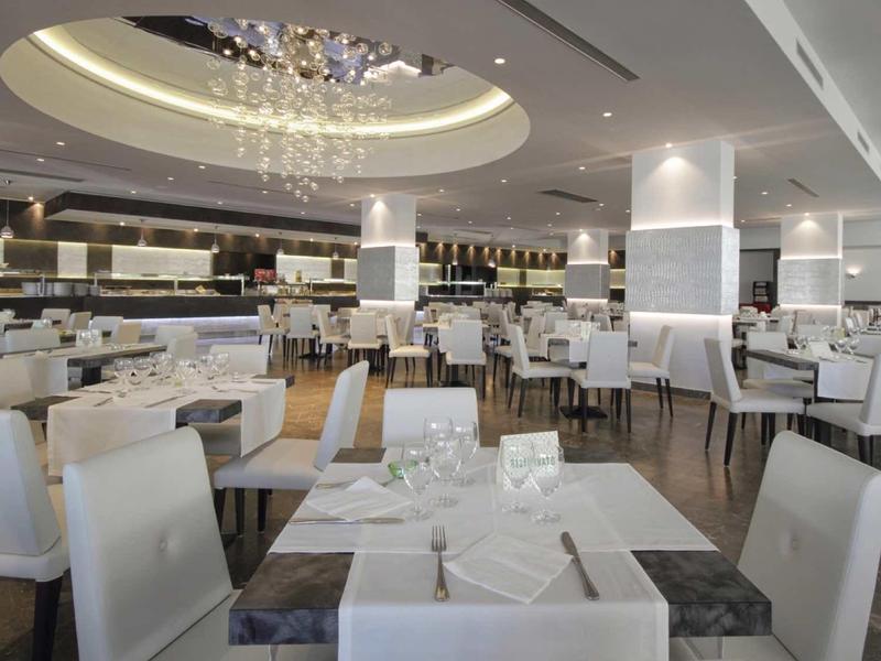 Salle à manger moderne et élégante avec des chaises blanches et un lustre décoratif dans un hôtel.