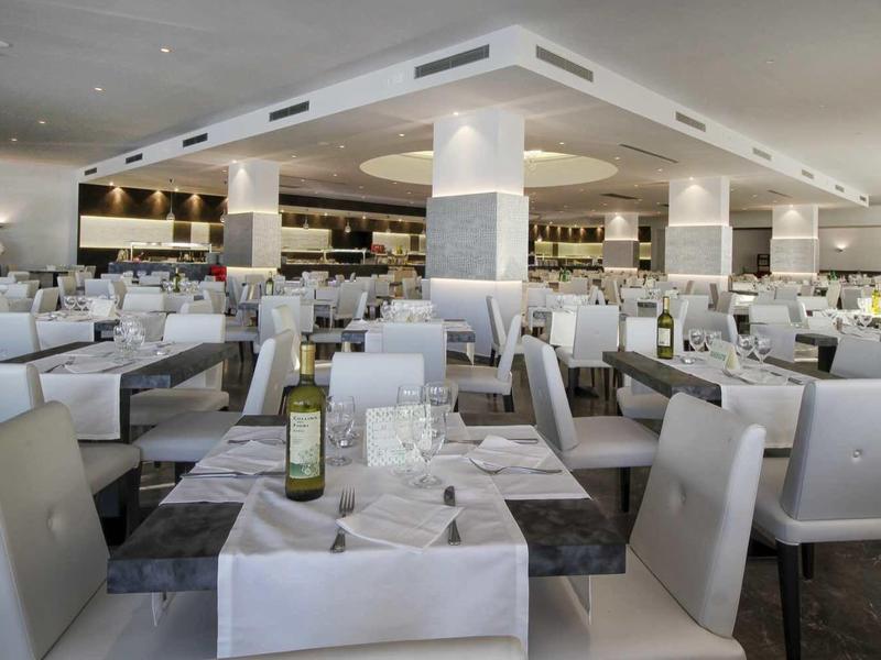 Restaurant d'hôtel moderne et lumineux avec des chaises blanches et des tables dressées.
