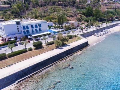 Pohled na hotel u pobřeží s čistou modrou vodou a pobřežní promenádou.