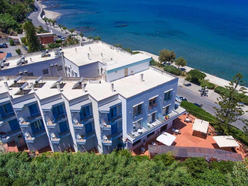 Moderní hotel s bílou fasádou přímo u moře s výhledem na pobřeží.