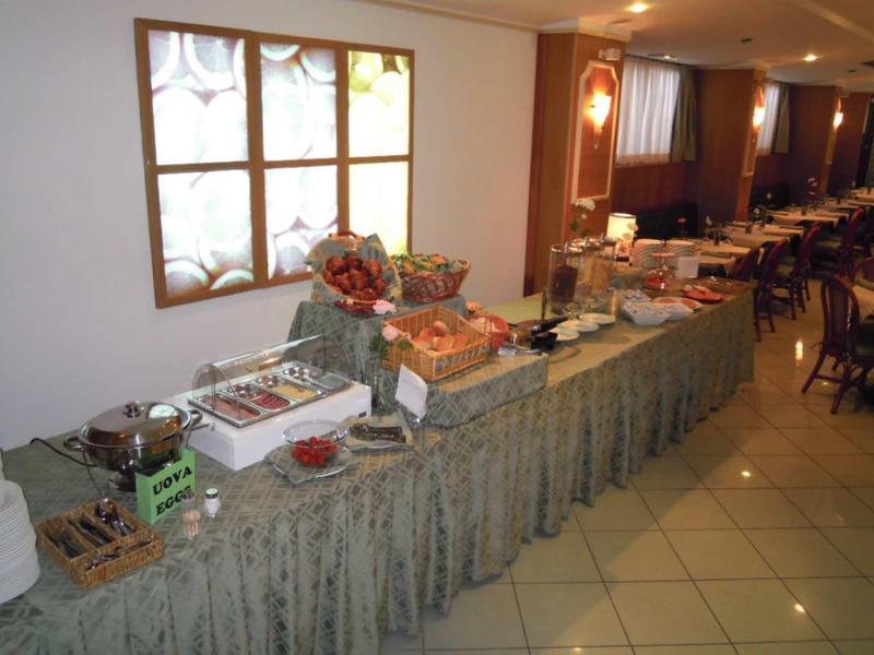Buffet con vari piatti e tavolo apparecchiato in un ristorante.