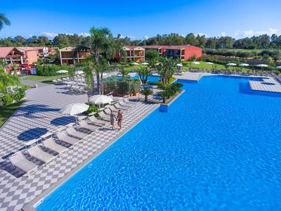 Duży niebieski basen z leżakami i palmami w hotelowym kurorcie przy słonecznej pogodzie.