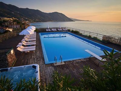 Large pool and hot tub with sea view at sunset at a hotel.