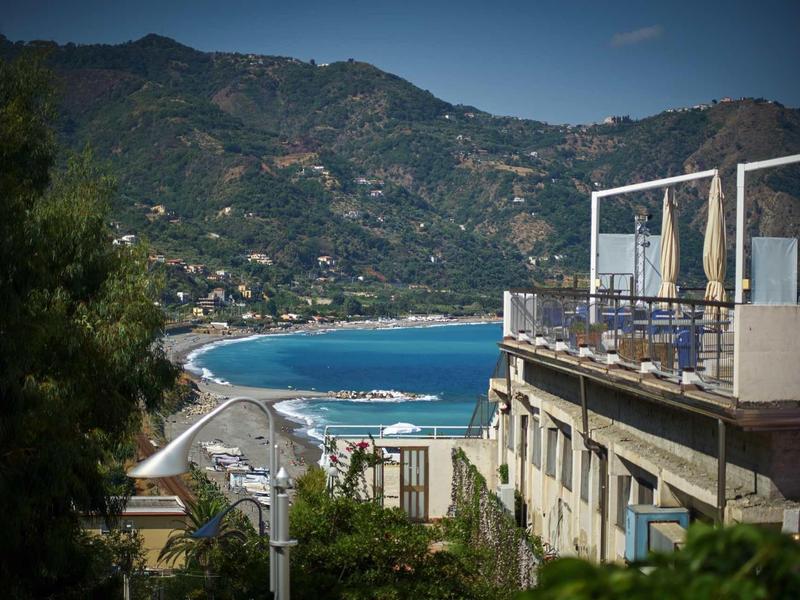View of a coastal town with beach and mountains in the background under clear sky.