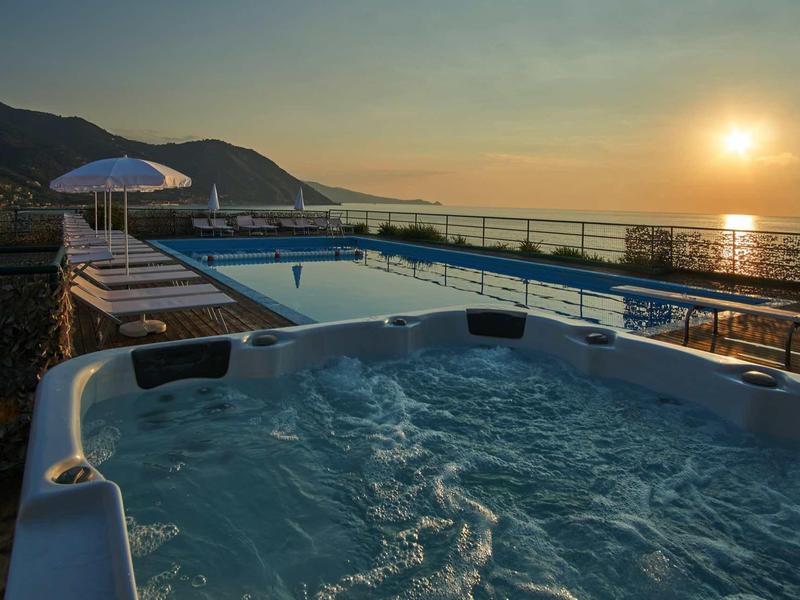 Hot tub and pool overlooking the sea at sunset in a vacation spot.