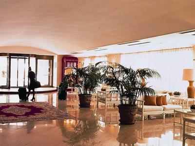 Luxusní hotelová lobby s posezením, velkými okny a jasnými lampami