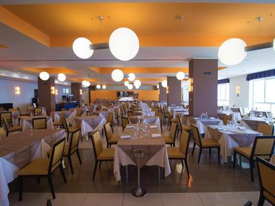 Grote moderne hotel eetruimte met gedekte tafels en stoelen onder bolvormige hanglampen.