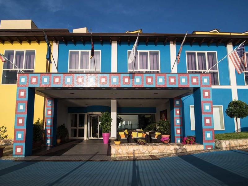 Ingang van een hotel met kleurrijk blauw en geel gevelontwerp en zitgedeelte bij daglicht