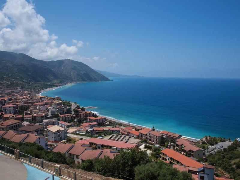 Uitzicht op een kustplaats met rode daken en blauwe zee op een zonnige dag