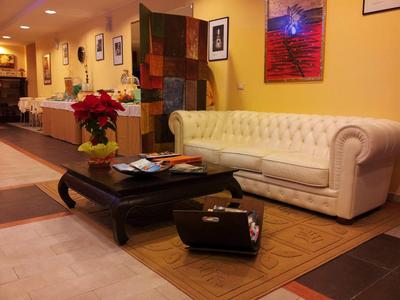 Elegant hotel lobby with white leather sofa, large coffee table, and accents like a suitcase and plants.