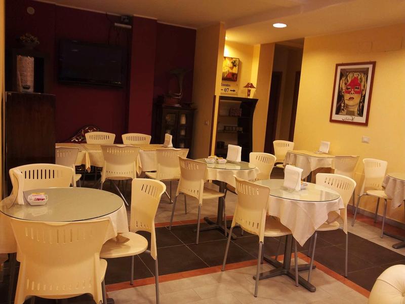 Interior view of a restaurant with set tables and white chairs under warm lighting.