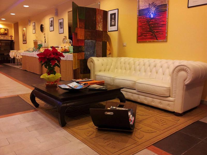 Elegant hotel lobby with white leather sofa, large coffee table, and accents like a suitcase and plants.