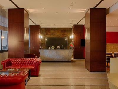 Elegante hotel lobby met rode leren banken en een moderne receptiebalie.