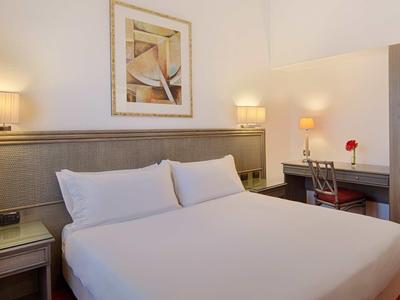 Camera d'hotel moderna con letto grande, comodini, scrivania e decorazione da parete.