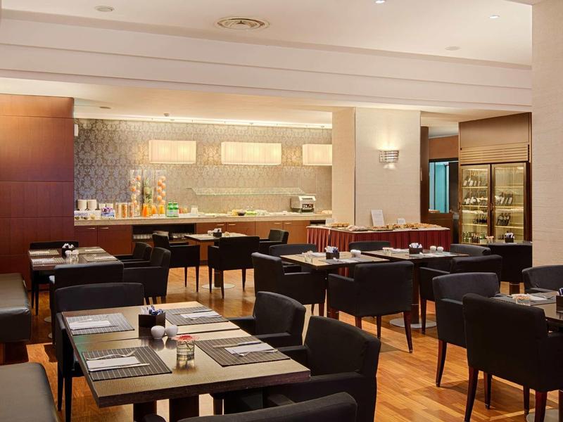 Ristorante d'hotel moderno con sedie scure e pavimenti in legno in un ambiente elegante.