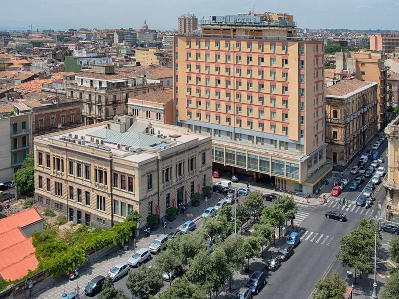 Vista urbana con un hotel su più piani e edifici circostanti con tempo soleggiato.