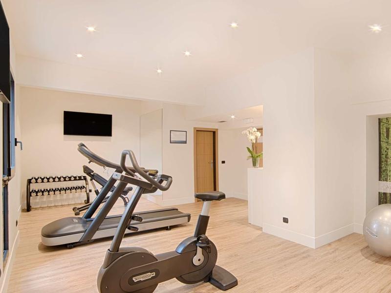 Palestra luminosa con cyclette, tapis roulant e pesi in design moderno.