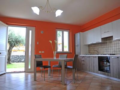 Cocina luminosa con paredes naranjas, mesa de comedor, sillas y vista al jardín.